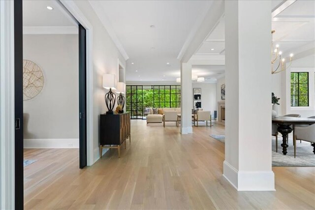 hall featuring light hardwood / wood-style flooring, an inviting chandelier, and ornamental molding