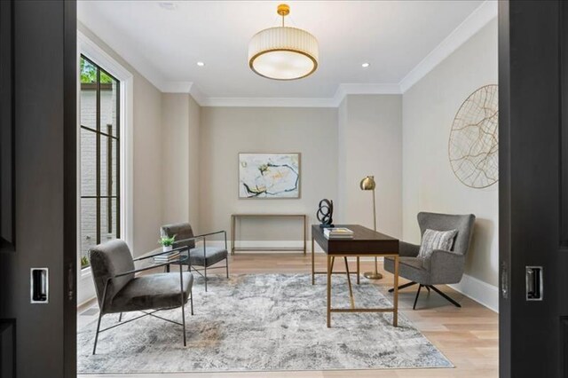 sitting room with light wood-type flooring and ornamental molding