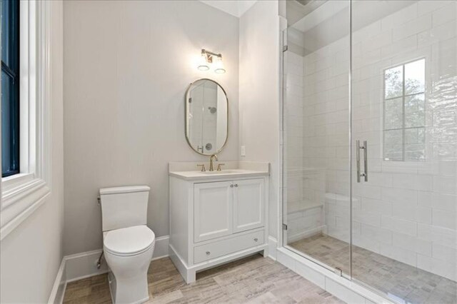 bathroom featuring vanity, toilet, and a shower with door