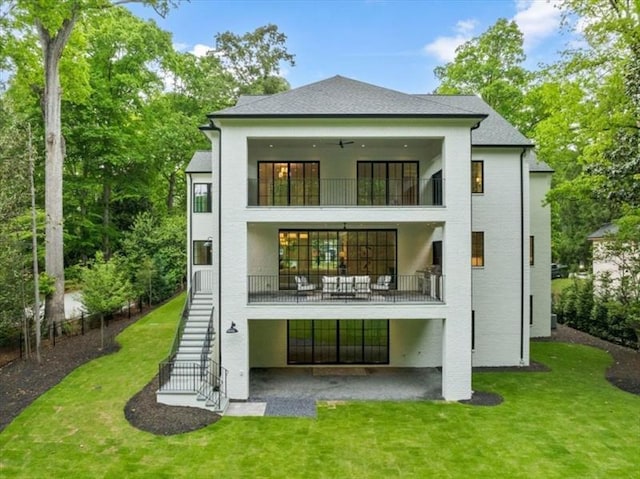 back of property featuring ceiling fan, a balcony, and a lawn