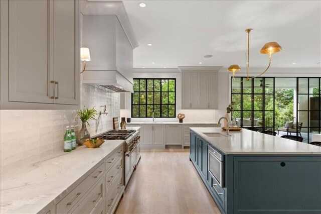 kitchen featuring sink, decorative backsplash, light hardwood / wood-style flooring, high end range, and decorative light fixtures