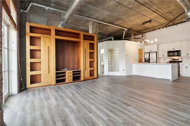 unfurnished living room featuring a towering ceiling and light hardwood / wood-style floors