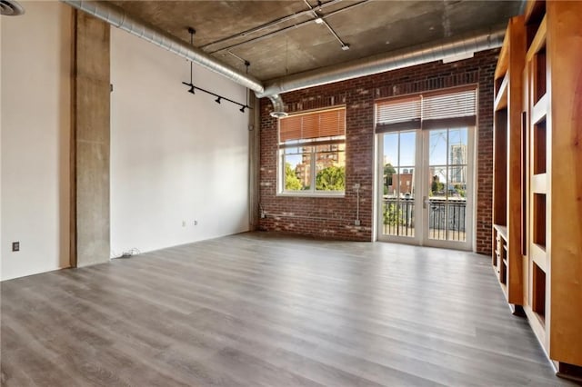 unfurnished room featuring brick wall, hardwood / wood-style floors, and a high ceiling