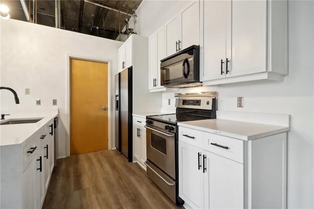 kitchen with appliances with stainless steel finishes, sink, white cabinets, and dark hardwood / wood-style flooring
