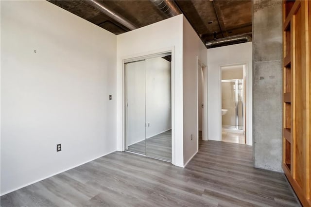 unfurnished bedroom featuring hardwood / wood-style flooring, ensuite bath, and a closet