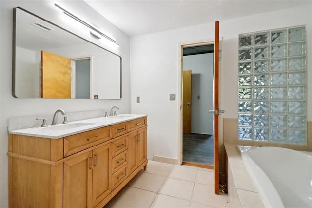 bathroom featuring tile patterned flooring, vanity, and tiled bath