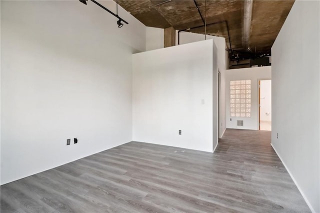 empty room with hardwood / wood-style floors and a high ceiling