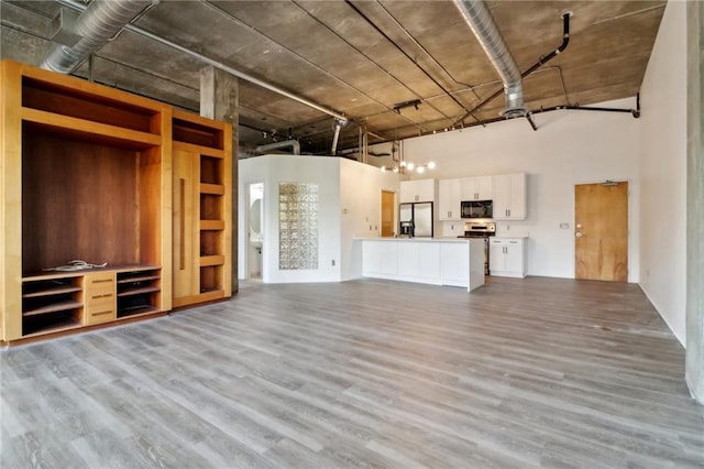 unfurnished living room featuring light hardwood / wood-style flooring and a high ceiling
