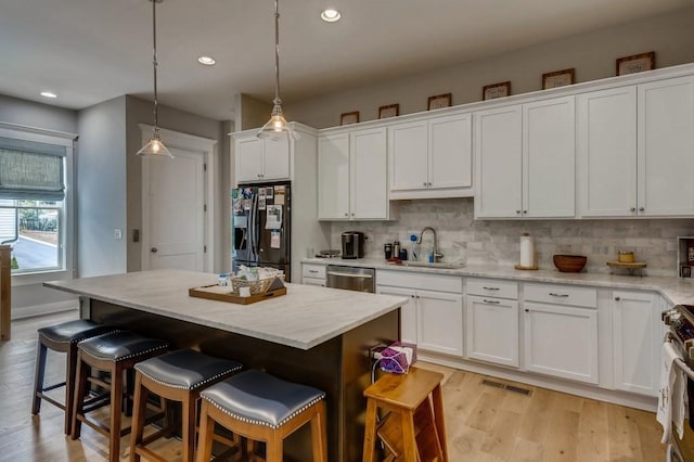 kitchen with appliances with stainless steel finishes, white cabinetry, hanging light fixtures, and a center island