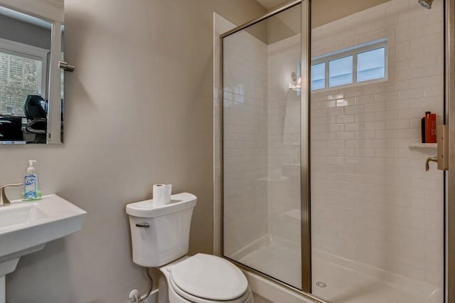 bathroom with an enclosed shower, sink, toilet, and a healthy amount of sunlight