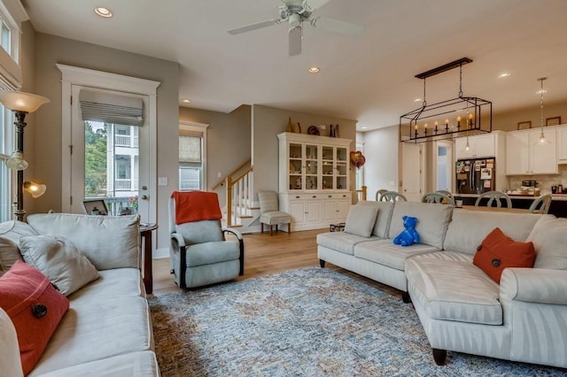 living room with ceiling fan with notable chandelier and hardwood / wood-style flooring