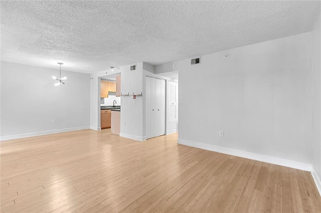 387 Ralph Mcgill Blvd NE Unit K, Atlanta, GA 30312 - unfurnished living room with a chandelier, a textured ceiling, a sink, light wood-type flooring, and baseboards