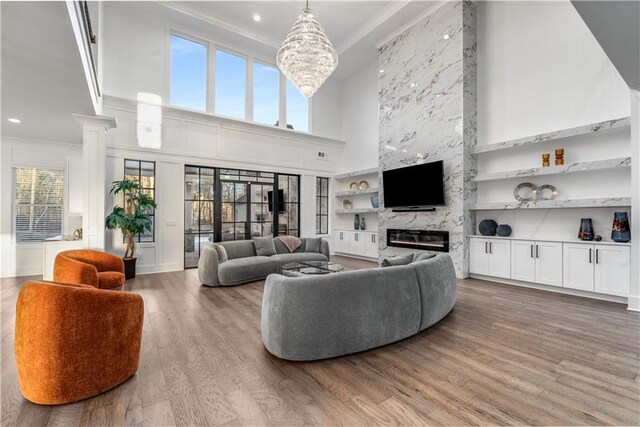 living room featuring a high ceiling, built in shelves, hardwood / wood-style flooring, and a high end fireplace