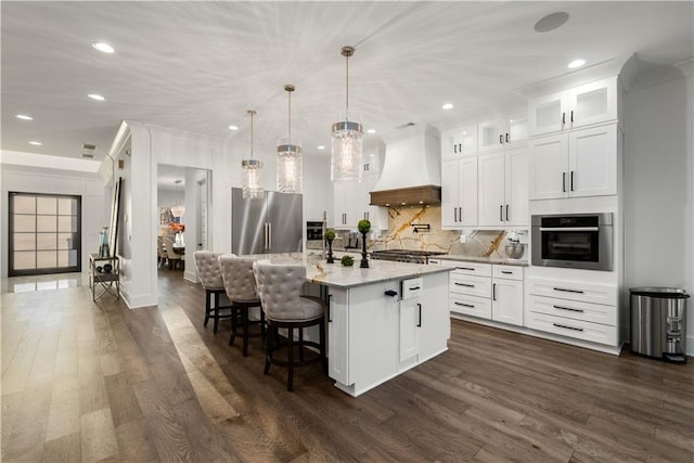 kitchen featuring dark hardwood / wood-style flooring, appliances with stainless steel finishes, an island with sink, custom exhaust hood, and white cabinets