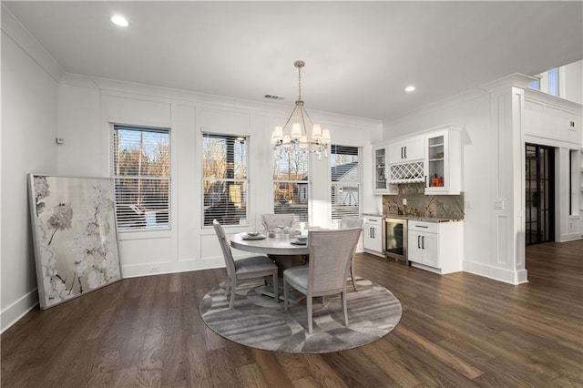 dining space featuring beverage cooler, dark hardwood / wood-style floors, a chandelier, and ornamental molding