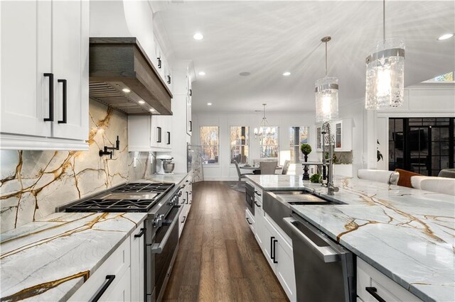 kitchen with light stone countertops, dark hardwood / wood-style flooring, pendant lighting, stainless steel appliances, and white cabinets