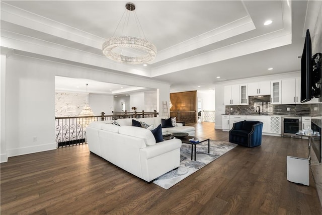 living room featuring dark hardwood / wood-style floors, beverage cooler, a notable chandelier, a tray ceiling, and sink