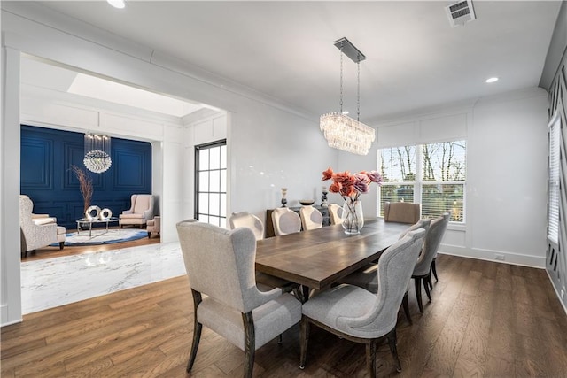 dining area featuring crown molding, dark hardwood / wood-style flooring, and a notable chandelier