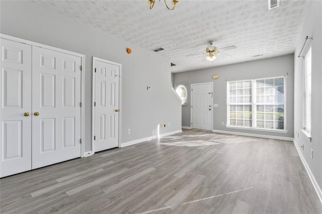 unfurnished living room with light hardwood / wood-style floors, a textured ceiling, and ceiling fan