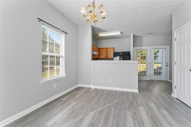 interior space with an inviting chandelier, a textured ceiling, and light wood-type flooring