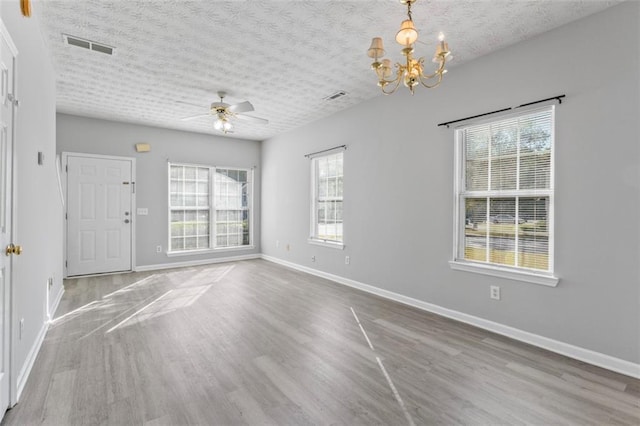 interior space with a wealth of natural light, hardwood / wood-style floors, and ceiling fan with notable chandelier