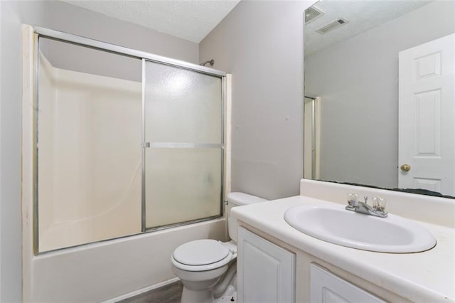 full bathroom featuring toilet, wood-type flooring, bath / shower combo with glass door, vanity, and a textured ceiling