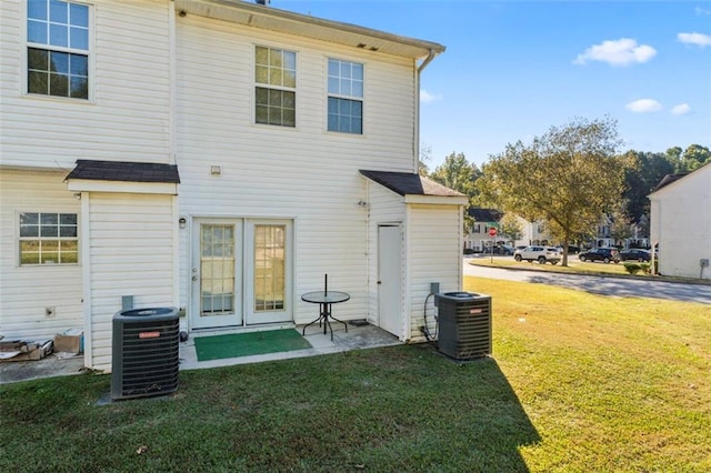 back of property with central air condition unit and a yard