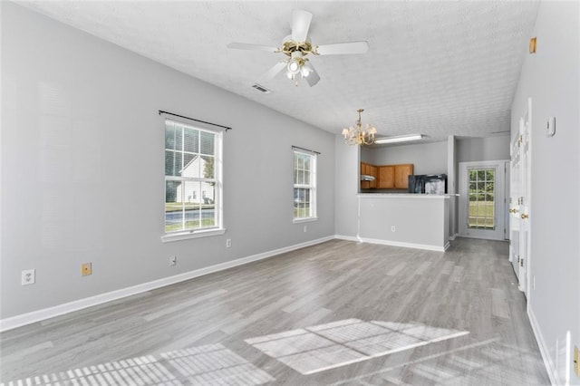 unfurnished living room with a textured ceiling, ceiling fan with notable chandelier, and light wood-type flooring