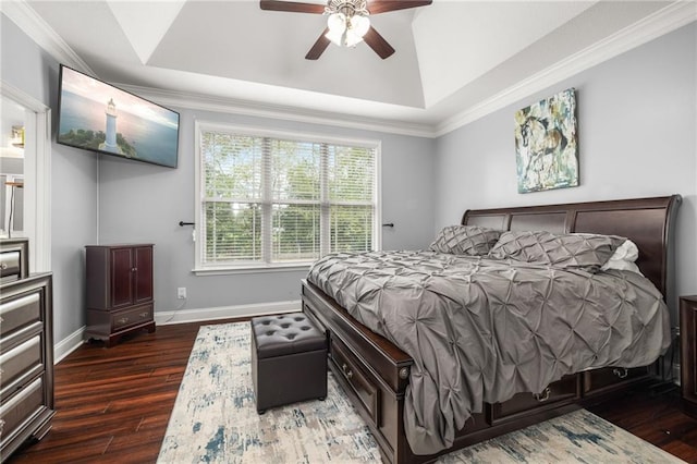 bedroom featuring ceiling fan, wood finished floors, baseboards, ornamental molding, and a tray ceiling