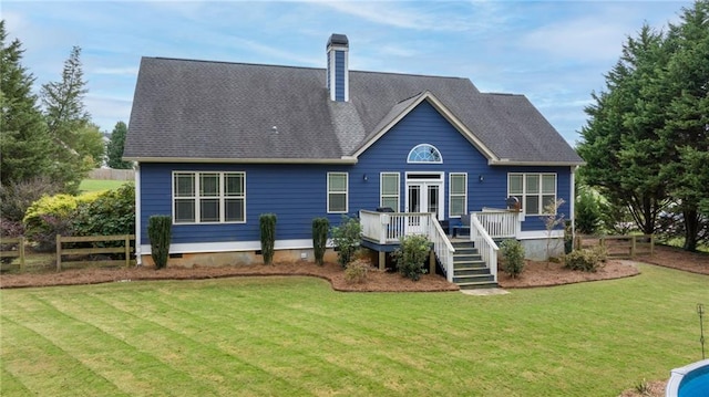 back of house with fence, a wooden deck, a chimney, french doors, and a yard