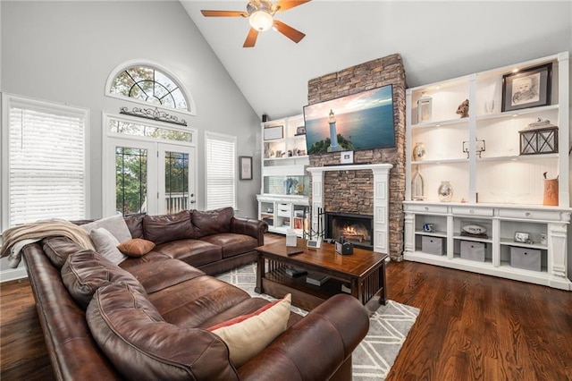 living room featuring a ceiling fan, high vaulted ceiling, a stone fireplace, and wood finished floors
