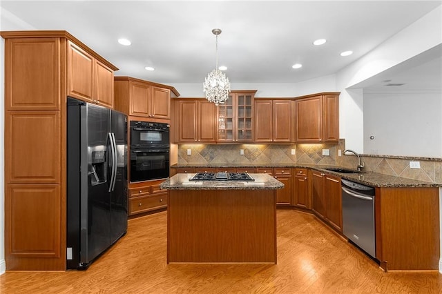 kitchen with a center island, sink, an inviting chandelier, stainless steel appliances, and dark stone counters