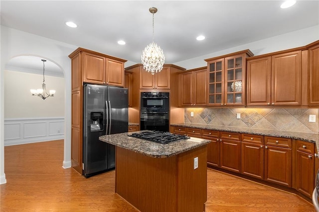 kitchen with decorative light fixtures, stainless steel appliances, dark stone counters, and a kitchen island