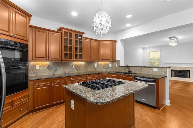 kitchen featuring stainless steel appliances, a center island, a chandelier, pendant lighting, and sink