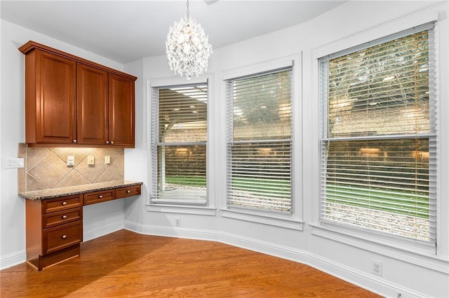 unfurnished dining area featuring dark hardwood / wood-style flooring, built in desk, and an inviting chandelier