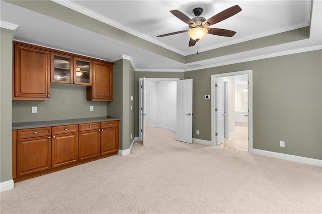 kitchen featuring light carpet, ceiling fan, crown molding, and a tray ceiling