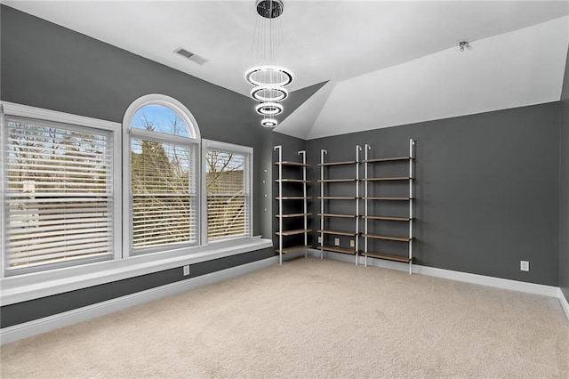 carpeted spare room with vaulted ceiling and a chandelier