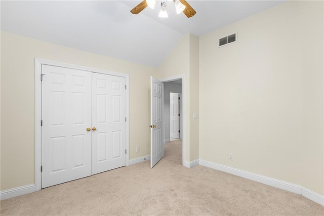 unfurnished bedroom with ceiling fan, a closet, light carpet, and vaulted ceiling