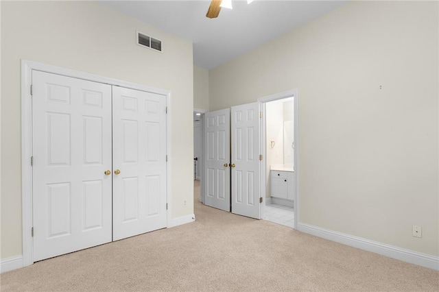 unfurnished bedroom with ceiling fan, light carpet, a closet, and ensuite bath