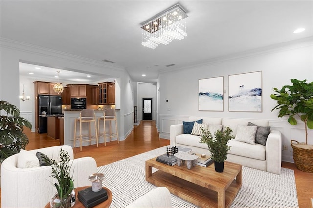 living room featuring light hardwood / wood-style flooring, crown molding, and a chandelier