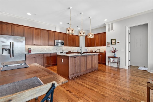 360 Chambers St Unit 402, Woodstock, GA 30188 - kitchen with stainless steel appliances, light wood-style flooring, decorative light fixtures, backsplash, and a center island with sink