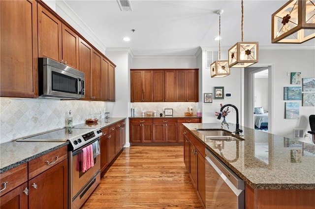 360 Chambers St Unit 402, Woodstock, GA 30188 - kitchen featuring appliances with stainless steel finishes, crown molding, dark stone countertops, light wood finished floors, and a kitchen island with sink