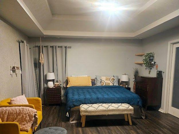 bedroom featuring dark hardwood / wood-style floors and a tray ceiling