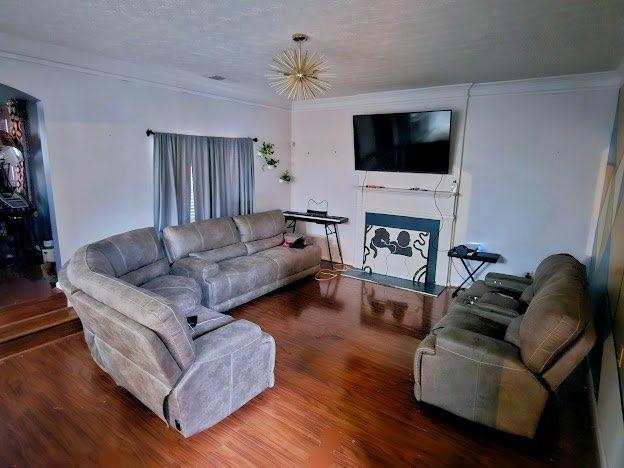 living room with ornamental molding, hardwood / wood-style floors, and a textured ceiling