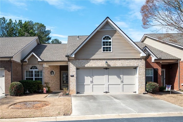 view of front facade featuring brick siding, an attached garage, concrete driveway, and roof with shingles