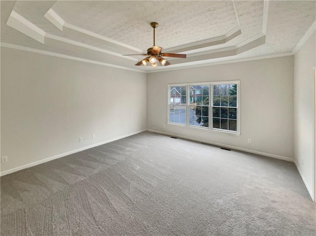 carpeted spare room with baseboards, crown molding, and a tray ceiling