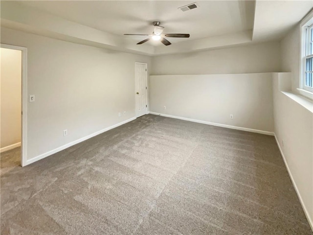 unfurnished room featuring a raised ceiling, baseboards, and visible vents