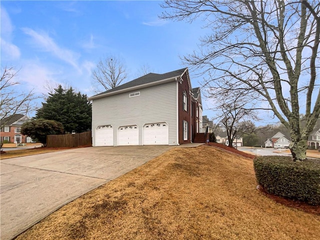 view of property exterior featuring concrete driveway, an attached garage, and fence