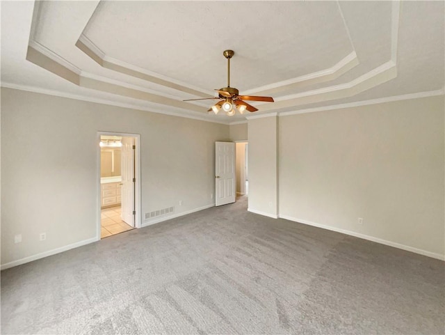 carpeted empty room with visible vents, ceiling fan, baseboards, and a tray ceiling