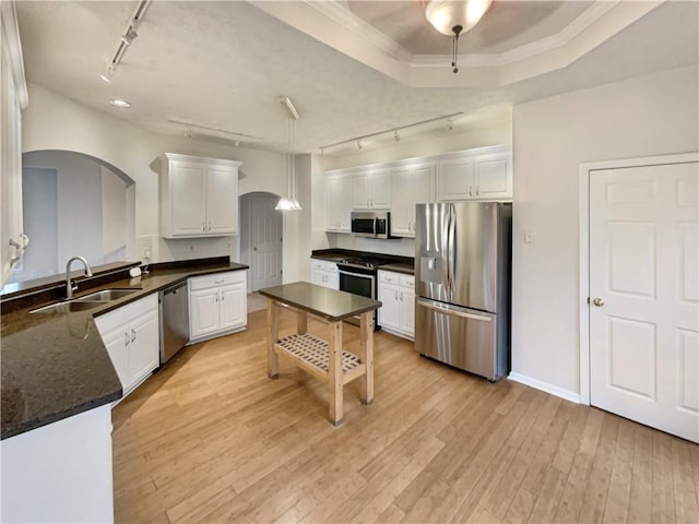 kitchen with light wood-style flooring, a sink, white cabinetry, arched walkways, and appliances with stainless steel finishes